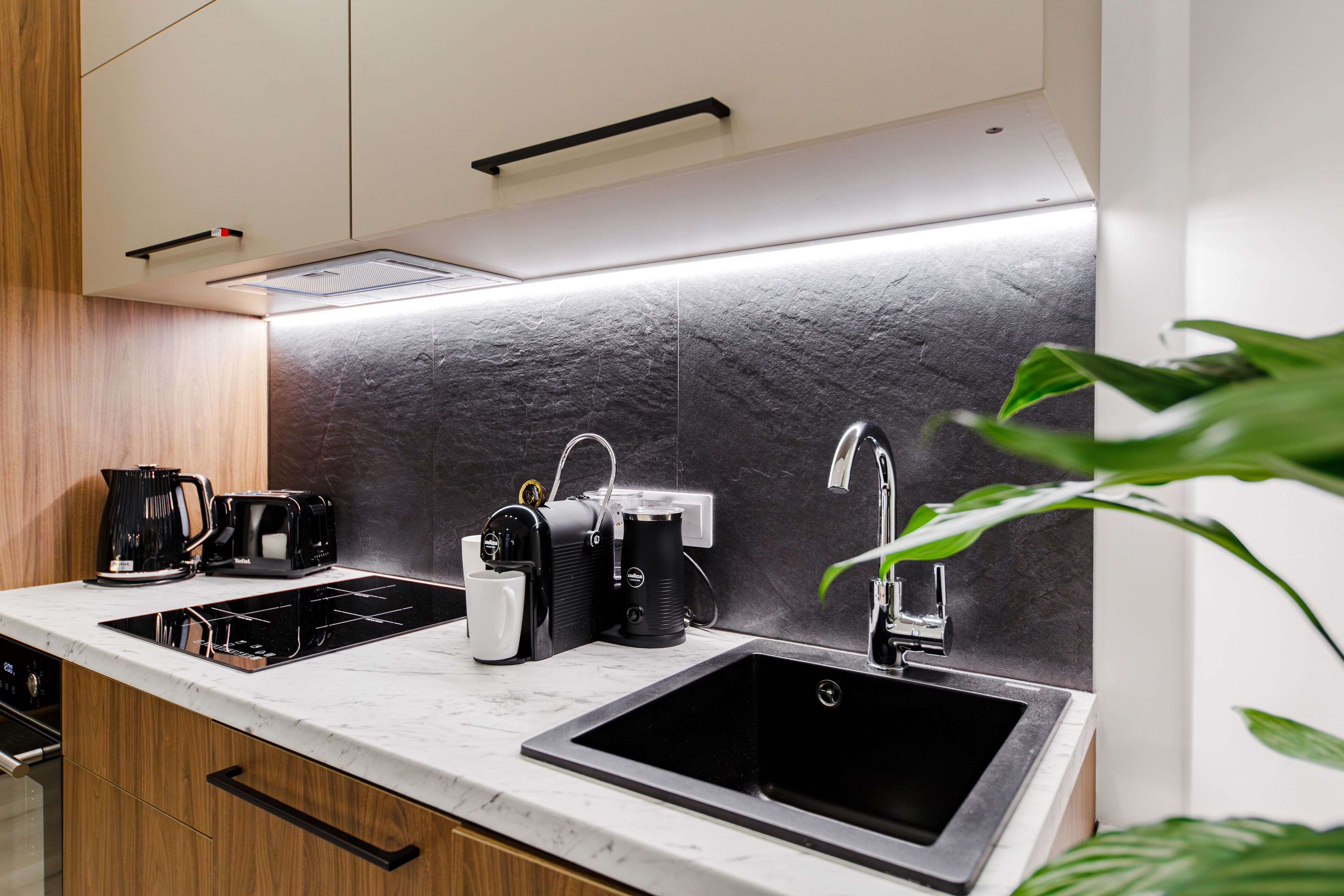 A modern kitchen with a black sink, a coffee maker, and a kettle on the counter.