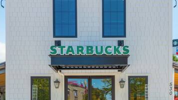 Una tienda Starbucks con fachada blanca, ventanas amplias y un letrero verde llamativo.