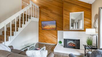 Una sala de estar moderna con una escalera, una chimenea y un espejo grande.