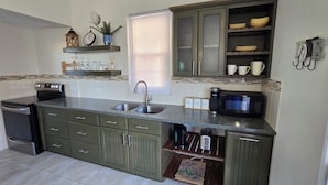 A compact kitchen with a sink, stove, microwave, and cabinets.