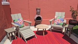 A patio with two Adirondack chairs, a small round table, and a wood-fired pizza oven.