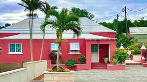 A red single-story house with a flat roof, a front door, and a small porch area.