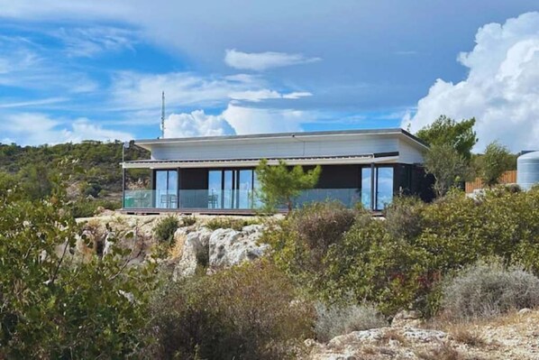 Een modern huis met een plat dak, grote ramen en een balkon.