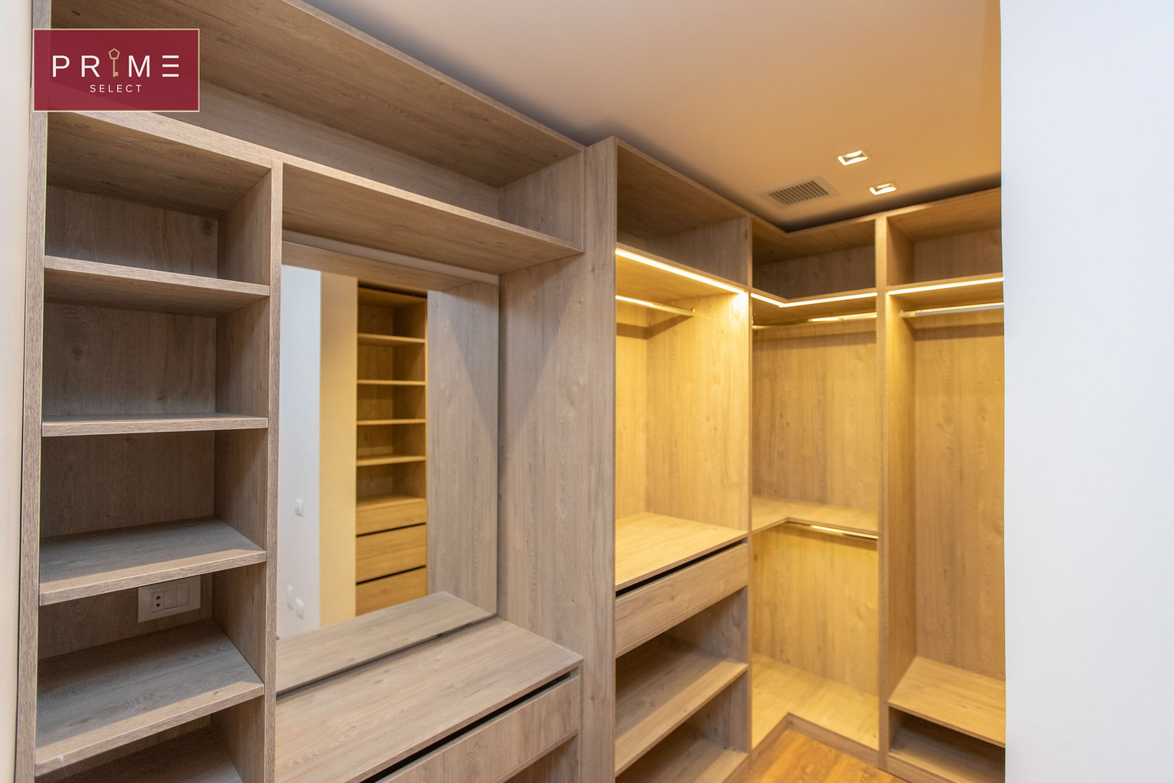 A walk-in closet with multiple wooden shelves and a mirrored section.