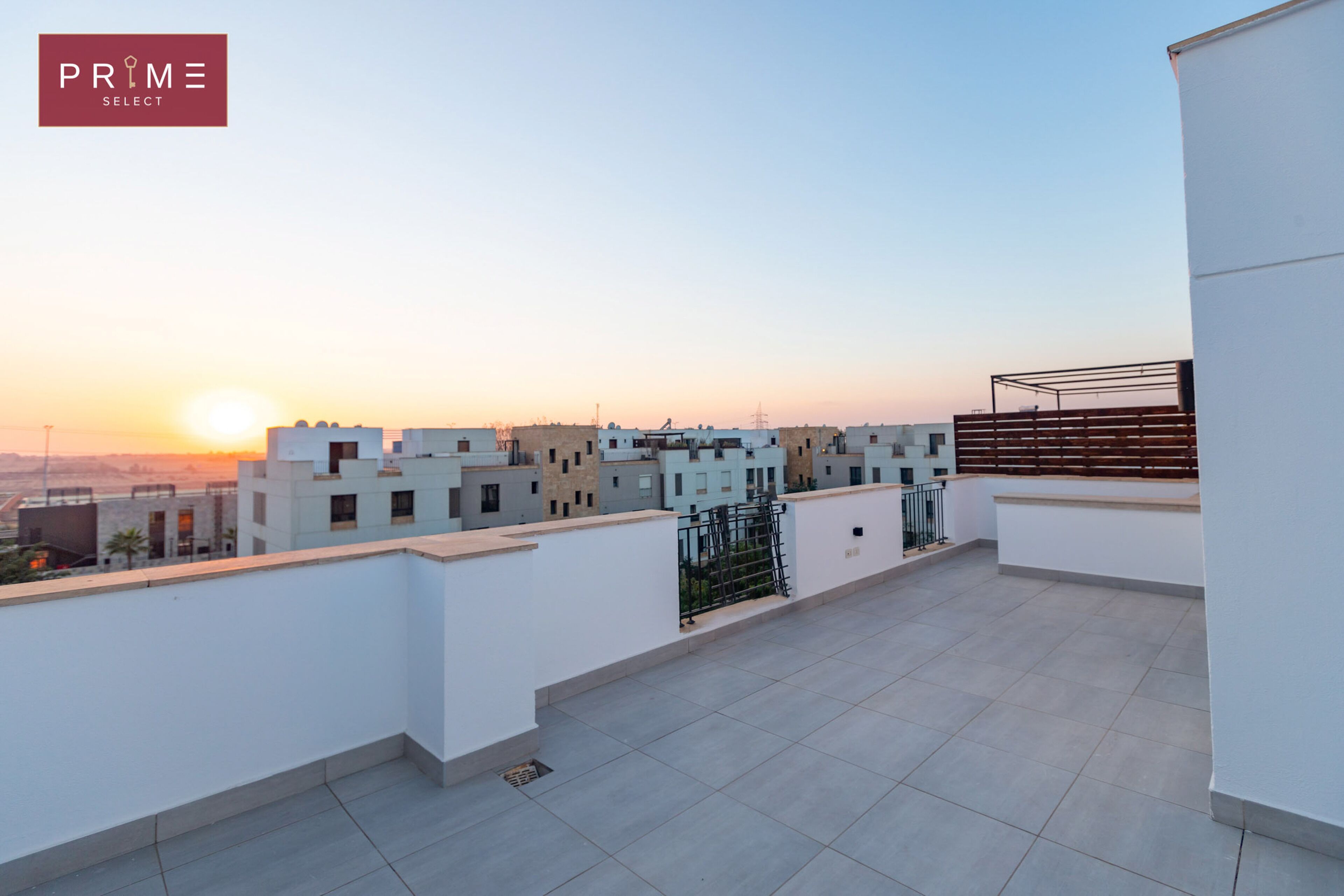 Eine Dachterrasse mit Blick auf umliegende Gebäude und einen Sonnenuntergang.