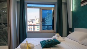 Une chambre d’hôtel avec un lit, une fenêtre donnant sur des immeubles et une salle de bain avec une porte en verre.