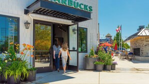 A Starbucks with a clear entrance, outdoor seating, and potted plants.