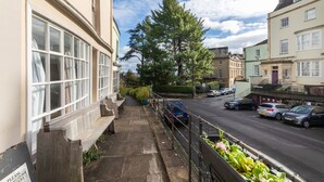 A residential street with a row of parked cars, a bench, and a row of houses with large windows. - Bright & Quirky 3BD Home - Wellington Terrace! (Bristol)