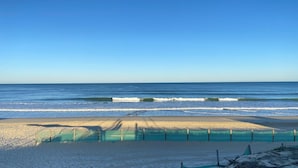 A beach with clear blue water, a sandy shore, and a wooden fence. - Le Châlet, Confort à L'orée de la Forêt et la mer (Mimizan)