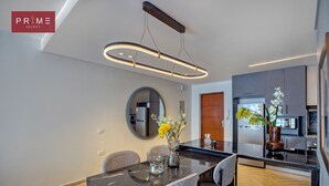 A modern dining area with a marble table, grey upholstered chairs, and a contemporary pendant light. - Prime Select Galleria moon valley (New Cairo)