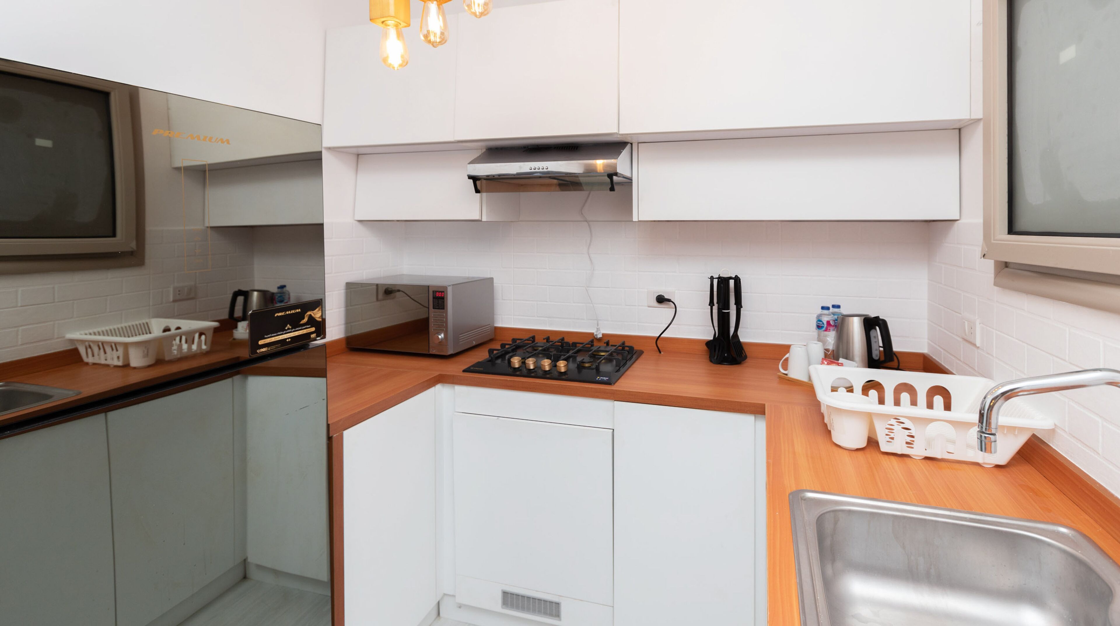 Una cocina moderna con armarios blancos, horno empotrado, microondas y pileta de acero inoxidable.