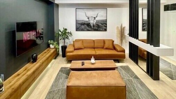 A modern living room with a sectional sofa, a coffee table, a TV, and a framed picture on the wall.