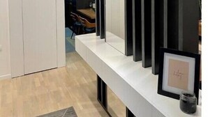 A modern interior with a white console table, a large mirror, and a black vertical panel.