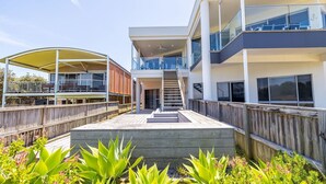 A modern multi-story building with a covered outdoor area, a staircase, and a wooden deck. - Birubi First Wave, 45a Ocean Ave - pet friendly, waterfront, waterviews, air con, Wi-Fi (Anna Bay)