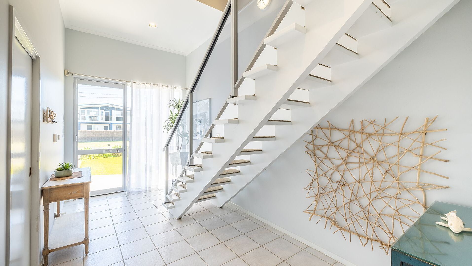 Un escalier moderne doté d’étagères intégrées, offrant une vue sur l’extérieur et agrémenté d’un élément décoratif mural.