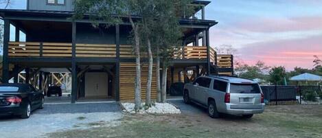 A modern two-story building with a garage and a covered parking area.
