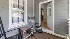 A porch with a rocking chair, a small table, and a door leading to an interior hallway.