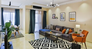 Una sala moderna con un sofá gris, un sillón naranja y una alfombra estampada.