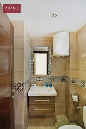 A bathroom with a white sink, two blue bottles, a mirror, and a toilet.