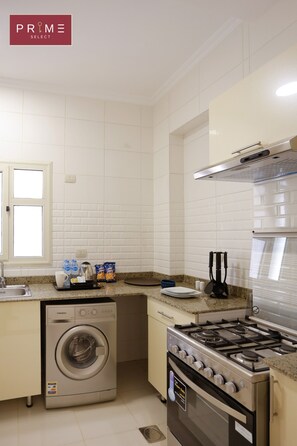 A compact kitchen with a washing machine, stove, and a window.