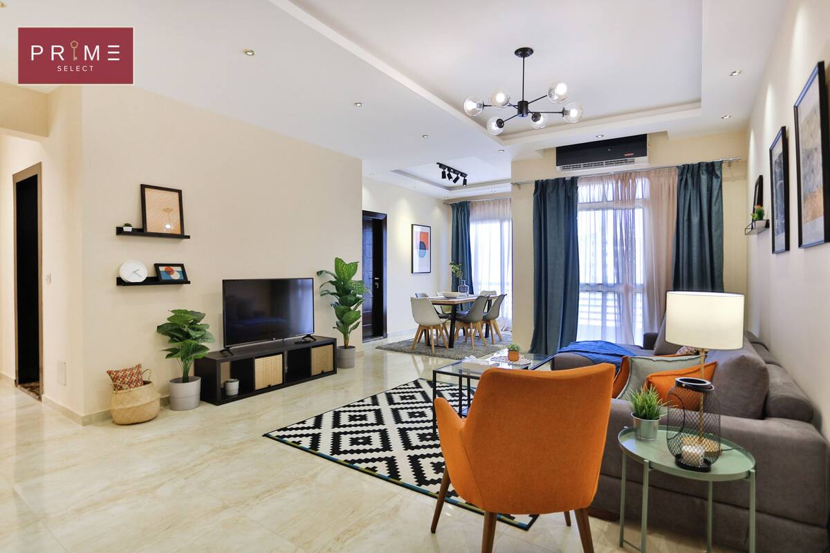 Uma sala de estar moderna com televisão, sofá, mesa de jantar e cadeiras.