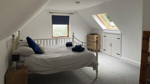 A bedroom with a bed, a window, a skylight, a wardrobe, and a nightstand. - Cosy Cotswold Coachhouse - Rural and quiet (Chalford)