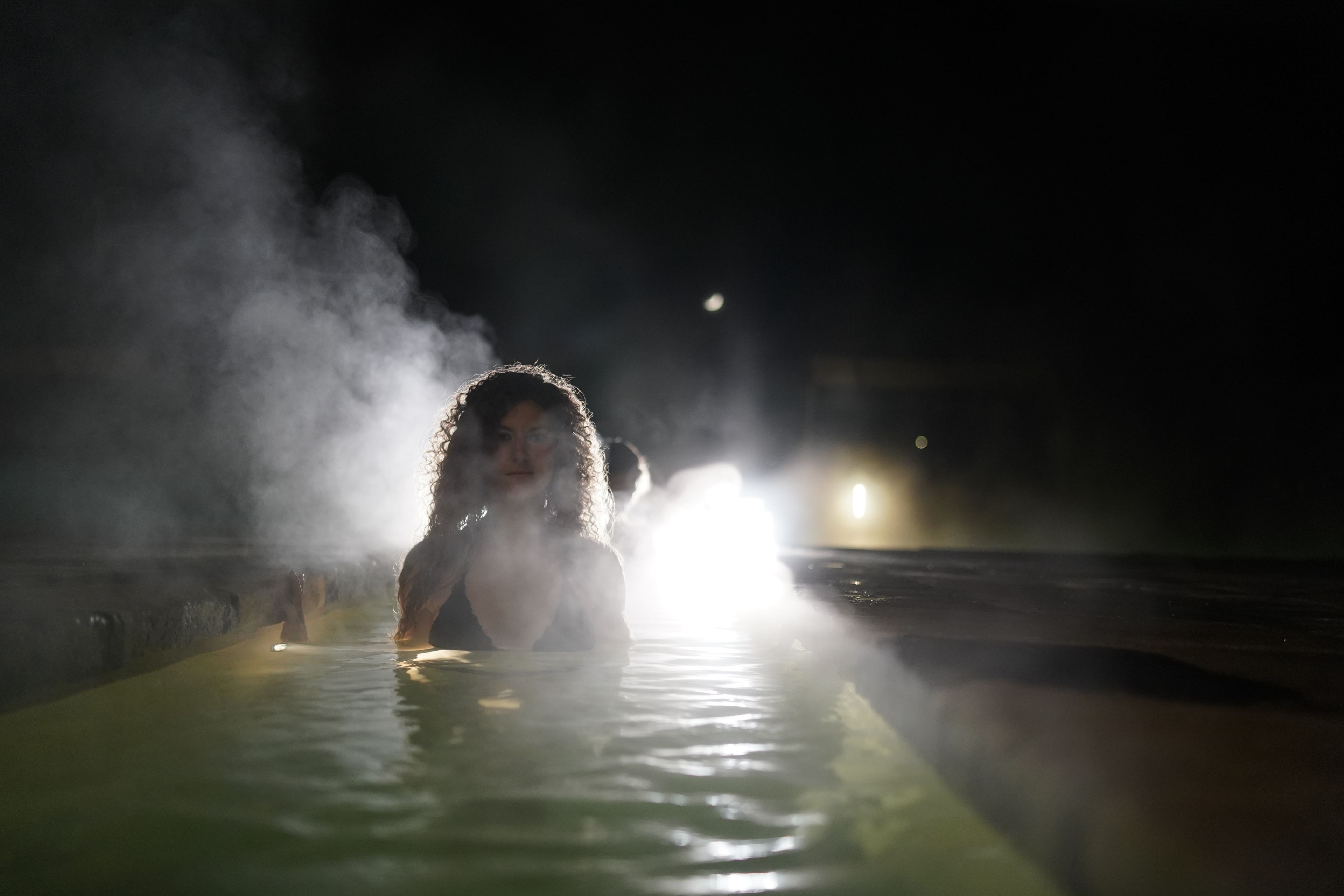 A person in a steam bath with a moon in the background.