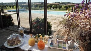 A breakfast table with a view of a swimming pool and vineyard. - Masseria Rifisa AgriResort (Caprarica di Lecce)