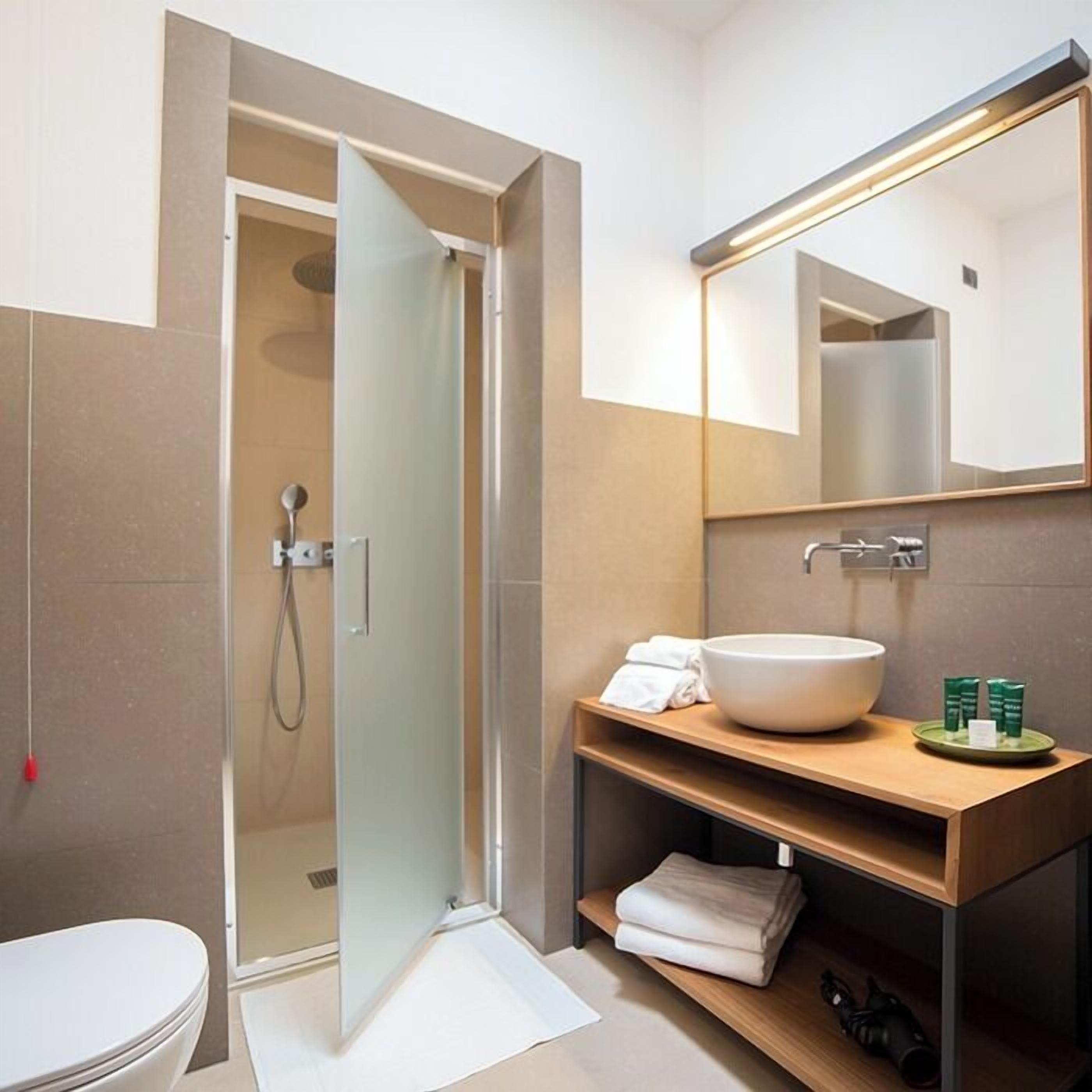 Ein modernes Badezimmer mit Duschabtrennung aus Glas, einem weißen Waschbecken und einem Spiegel darüber.