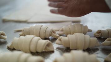 Une main façonne la pâte en différentes formes sur une surface en bois.