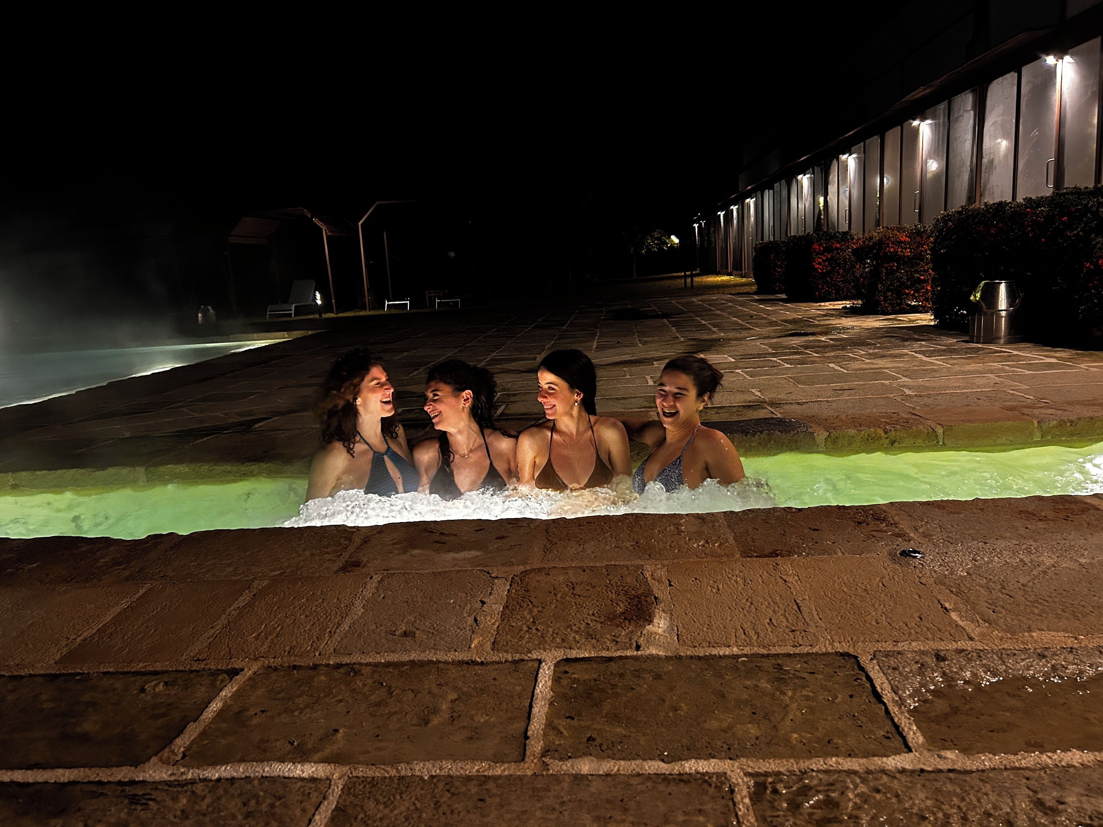 Un grupo de personas en un jacuzzi por la noche.