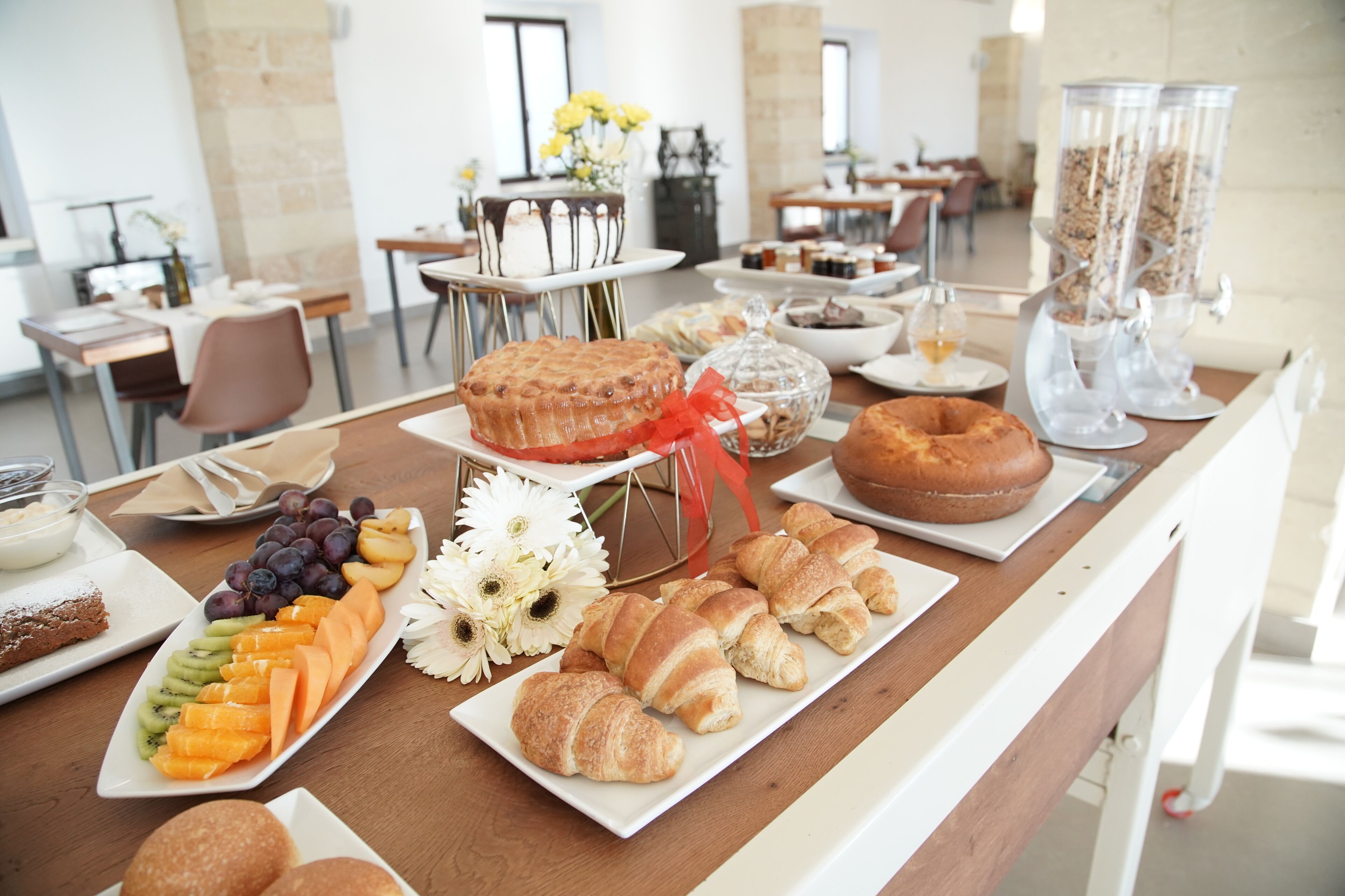 A buffet table with various food items including fruits, pastries, and a cake.