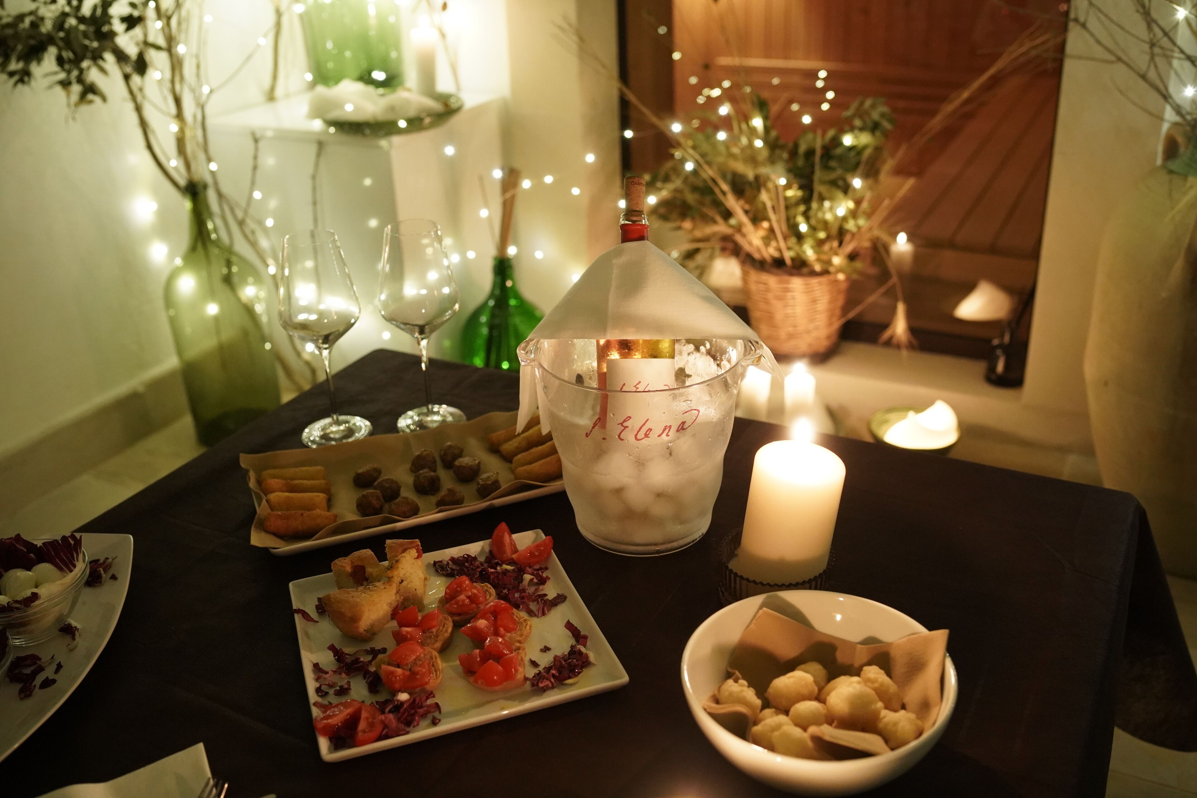 Una mesa de comedor con varios platos, una vela y una botella de champán.