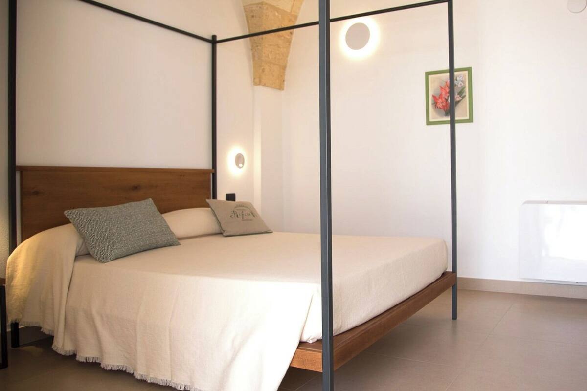 A bedroom with a four-poster bed, a wooden headboard, and a single bedside table.