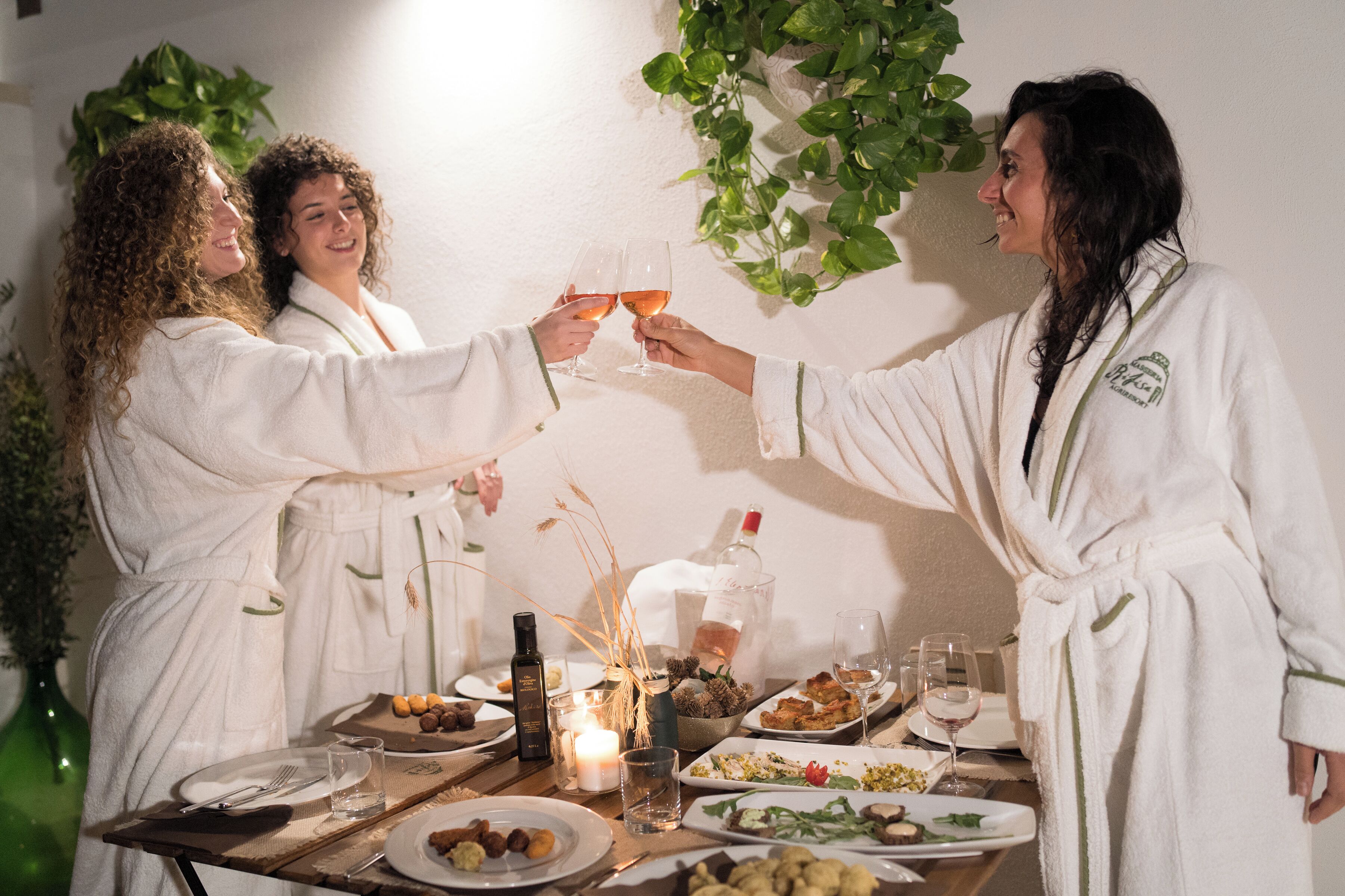 Een eettafel met diverse gerechten en glazen, omringd door mensen in witte gewaden.