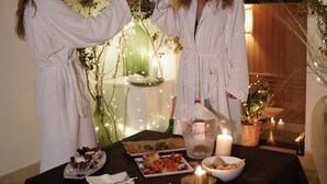 Two people in white robes at a table with food, candles, and a decorative setting. - Masseria Rifisa AgriResort (Caprarica di Lecce)