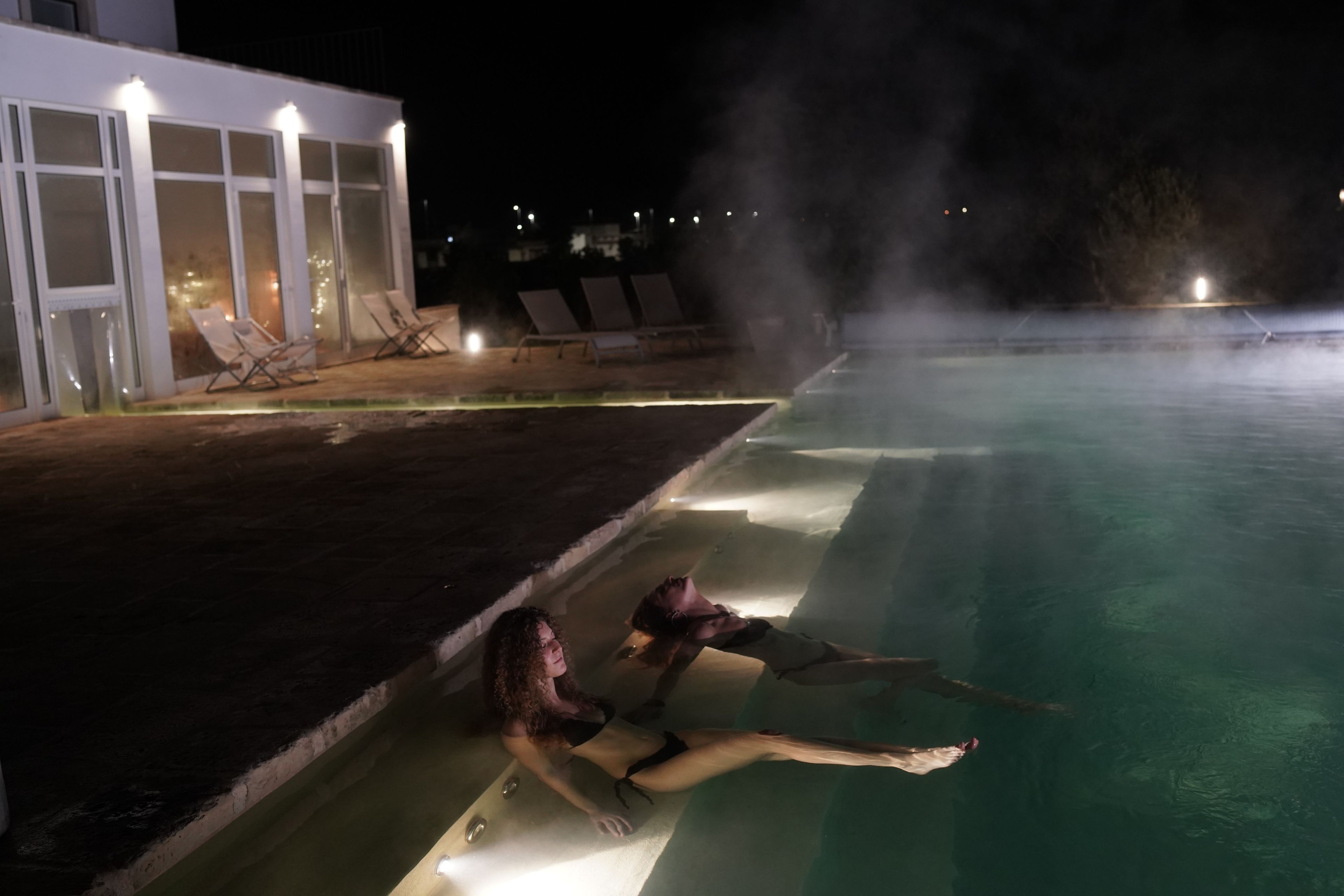 Een zwembad met een jacuzzi en ligbedden.