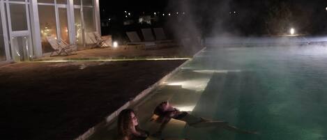 Een zwembad met een jacuzzi en ligbedden.