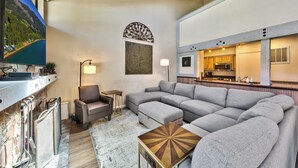 A modern living room with a sectional sofa, a flat-screen TV, and a kitchen area visible through an open doorway. - Lakeland Village #481 - Family Footprints by the Lake-Sleeps 10 (South Lake Tahoe)
