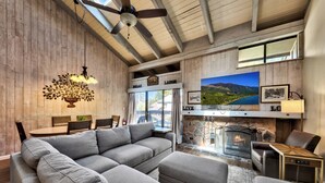 A cozy living room with a fireplace, a large sofa, and a dining area. - Lakeland Village #481 - Family Footprints by the Lake-Sleeps 10 (South Lake Tahoe)