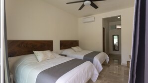 A hotel room with two beds, a ceiling fan, and a view of the hallway. - Petras (Puerto Escondido)