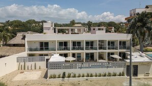 A modern hotel with a flat roof, multiple balconies, and a pool area. - Petras (Puerto Escondido)