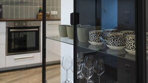 A modern kitchen with a glass display cabinet containing decorative cups and wine glasses. - Wohnen im Milchhäusle von Schnait (Weinstadt)