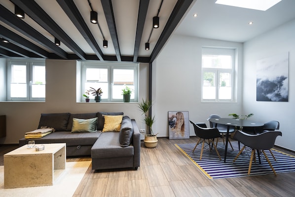 A modern living room with a sofa, coffee table, and dining area with chairs.
