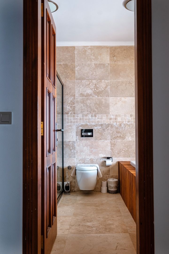 A narrow hallway leading to a bathroom with a toilet, a bidet, and a shower area.