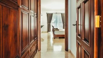 A hallway with wooden paneling and a bed in the background.