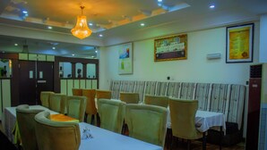 A dining area with tables and chairs, a chandelier, and wall decorations. - Forever Hotels and Suites (Owerri)