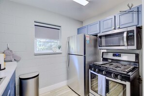 A compact kitchen with a stainless steel refrigerator, microwave, and gas stove. - Modern Studio with King Bed, Free Parking & Wi-Fi (Memphis)