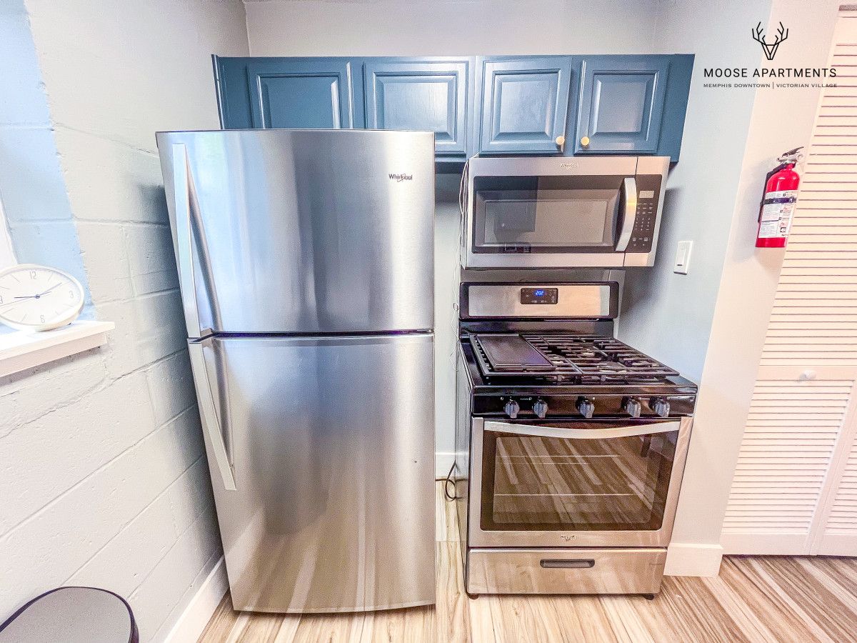 Una cocina con un refrigerador de acero inoxidable, un microondas y una estufa.