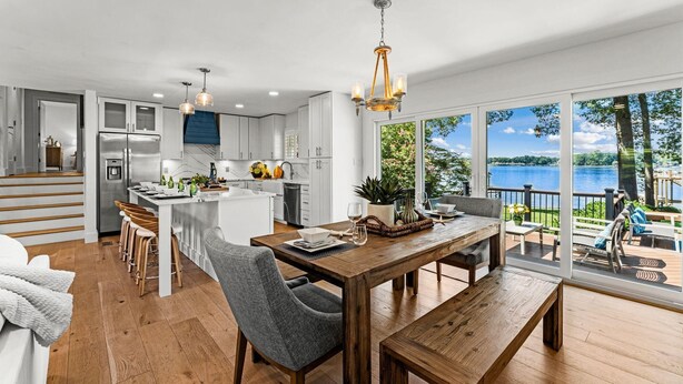 A modern kitchen with white cabinets, a stainless steel refrigerator, and a dining area with a wooden table and chairs. - Lakefront Living W/optional Boat Rental (Mooresville)